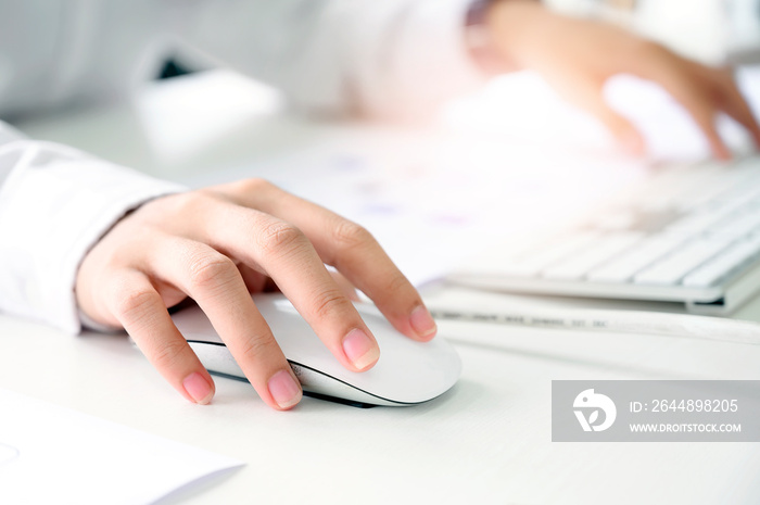 Closeup shot of female hand holding mouse and working with desktop computer.