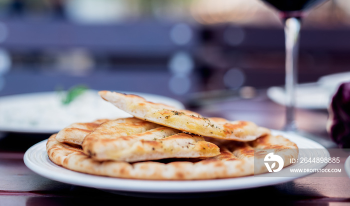 Griechisches Pita Brot mit Gewürzen vom Grill mit Rotwein im Garten serviert