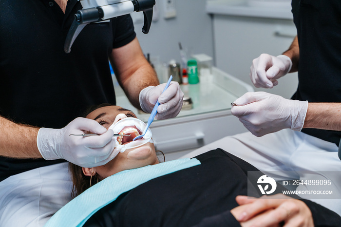 Male dentists with microscope and dental tools treating patients teeth at modern dental clinic offi