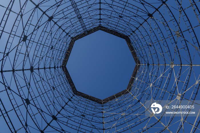 Uprisen angle view inside former gasometer, existing structure against blue sky.