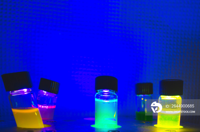 Multiple colourful close up photochemical reaction in glass vial under blue UV light in a dark chemistry laboratory