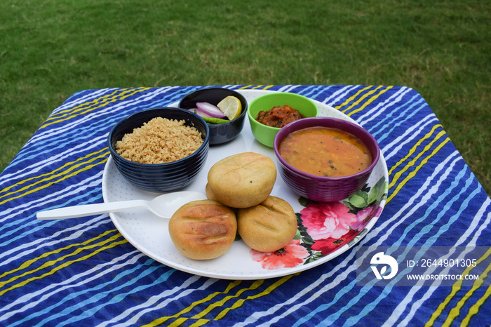 Rajasthani traditional food Dal baati also known as Dal bati or Daal baati with churma or choorma and onion greenchilly salad, garlic pickle, tomato pickle served in designer plate and bowls crockery