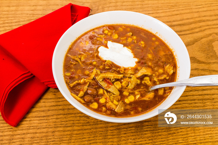 Chicken Enchilada Soup with Dollop of Sour Cream on Rustic Table