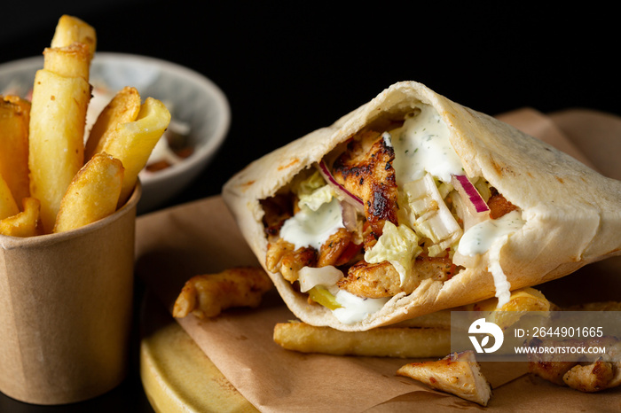 Close up of chicken and vegetables pita and potato fries