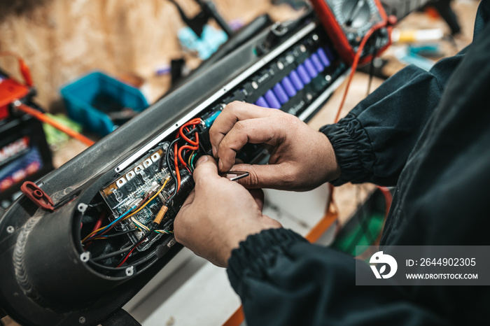 Man repairing electrical scooter in special workshop. Special workshop for repairing electrical scooters and bicycles.