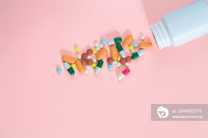 pills and medicine bottle on pink background,Blue capsule pills spread out of white plastic drug bottle on pink background. Pharmacy banner. Online pharmacy. Painkiller medicine and antibiotic drug