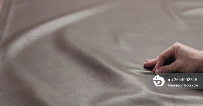 man hand checking brown leather piece closeup