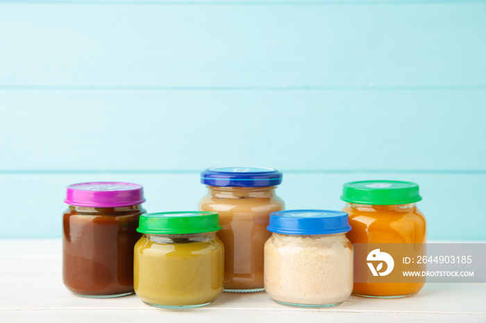 Jars of baby puree on light wooden background