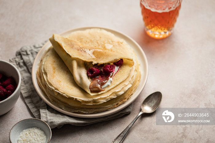 Assiette de crêpes à la crème de marron et framboises avec verre de cidre sur une table