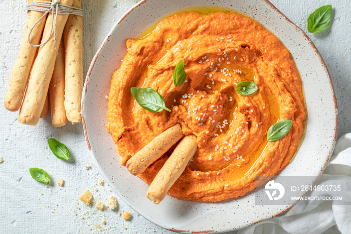 Homemade tomato hummus with grissini, basil and sesame