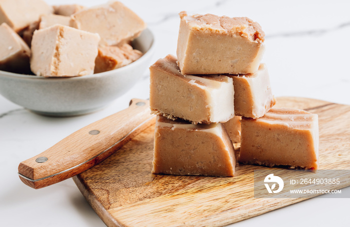 Raw vegan peanut butter fudge on a white marble background.