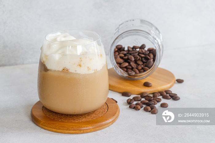 expresso frío con espuma de leche fría con café molido marrón y granos de café espolvoreado en una mesa blanca