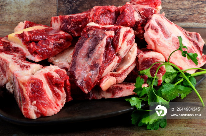 Raw meat with bone on clay plate and brown stone background.Raw meat with beef bone. Beef bone selection for soup