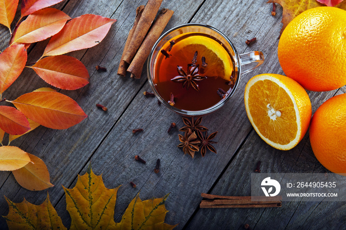 hot tea with spices and orange amid autumn leaves