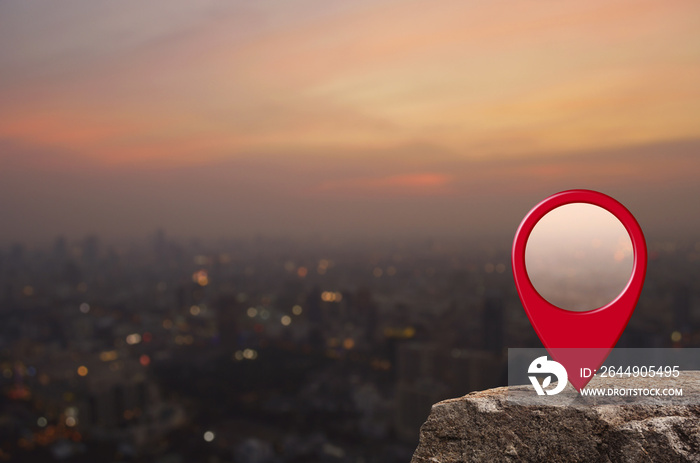 Map pin location button on rock over blur of cityscape on warm light sundown, Map pointer navigation concept