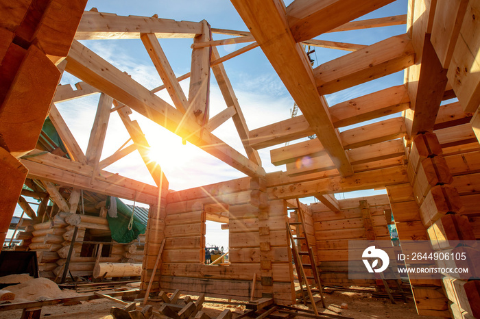 New house wooden log construction interior with exposed framing roof with sun light