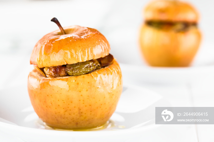 Fresh baked stuffed apple with walnut, almond, raisin, sultana, butter, sugar and cinnamon, a traditional autumn and winter dessert (Selective Focus on the front of the left apple)