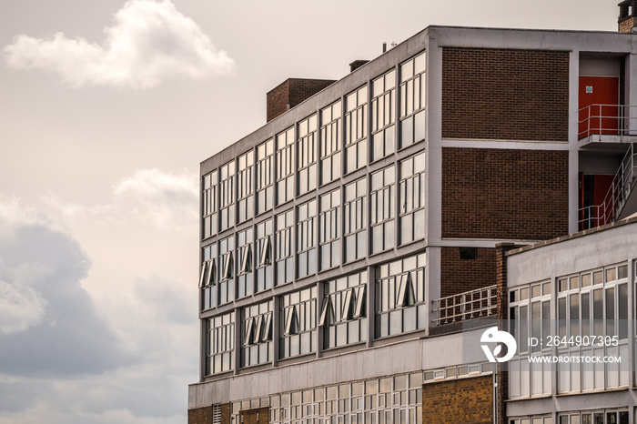 Old 1970’s concrete and brick office building block with sun shining in need of regeneration project to modernise