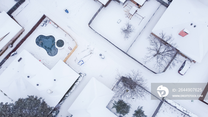 Suburban houses with swimming pools, playground and large backyard covered in thick snow near Dallas, Texas, USA