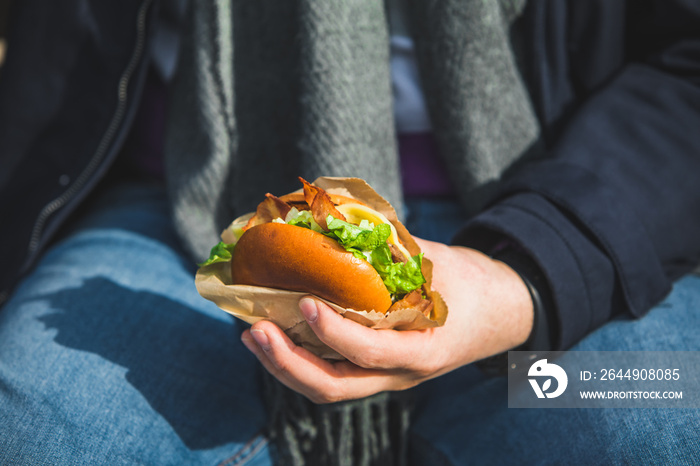 man hands close up holding burger with coffee cup