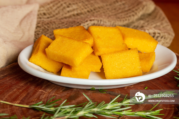 Portion of fried polenta . Polenta cubes.Typical Italian fried polenta. Fried corn sticks.