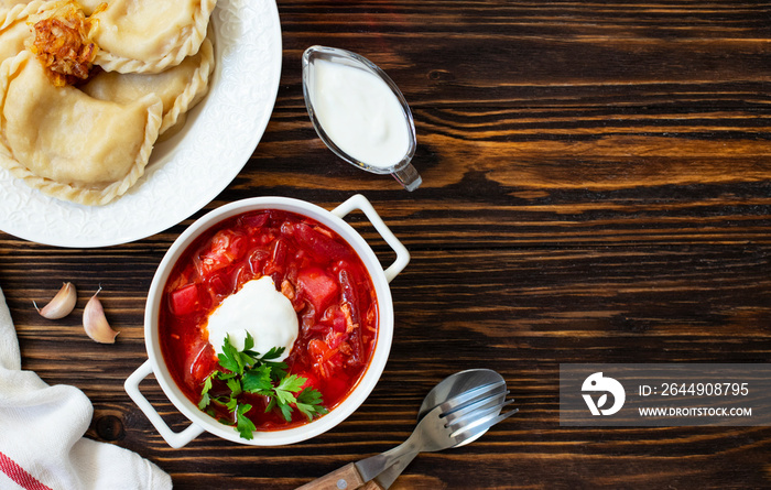 Eastern European food Ukrainian, Russian, Polish. Borscht and Varenyky, Vareniki. Traditional beetroot soup borscht and dumplings with potatoes served with sour cream and parsley on a wooden table