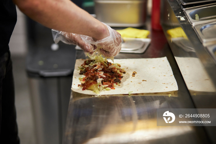 the process of cooking shawarma, the hands of the cook. Hands wear  gloves making takeaway shawarma. the process of cooking turkish fast food - shawarma or kebab.