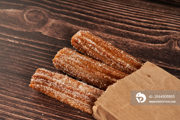 churros coming out of paper bag on wooden table