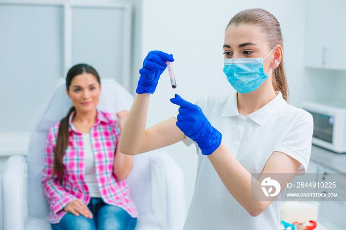 Serious nurse with blood sample of her patient in the clinic