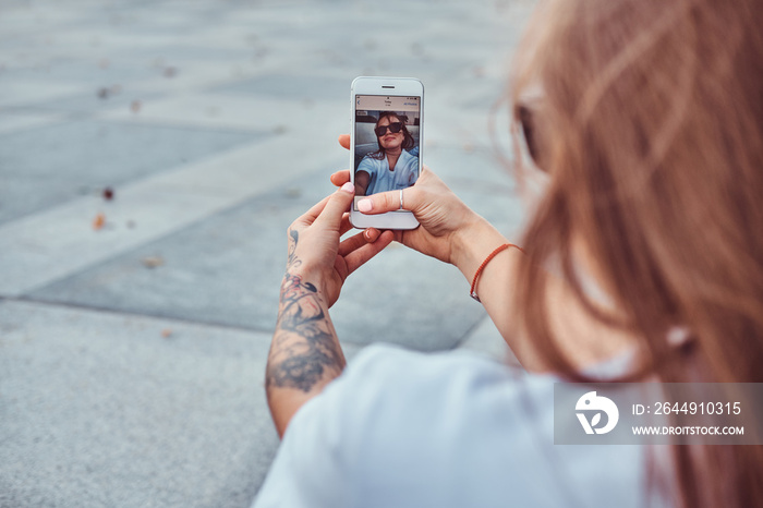 Close-up photo of young girl in sunglasses makes a selfie outdoors.