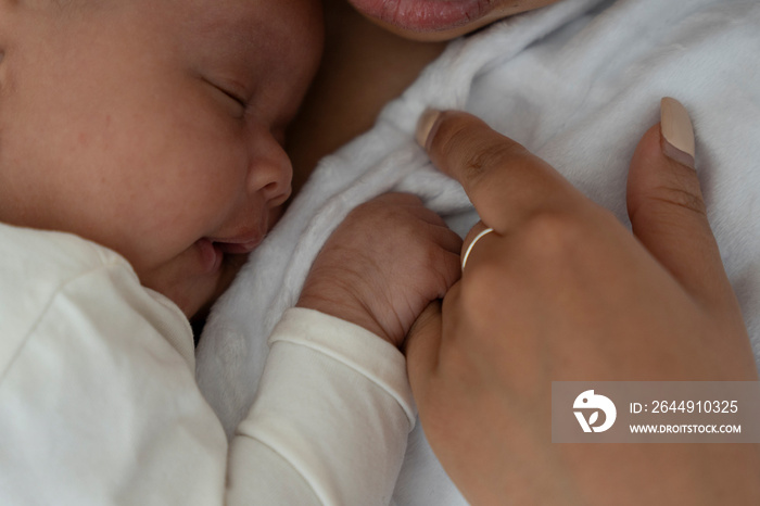 Close-up view of newborn baby girl holding mother finger