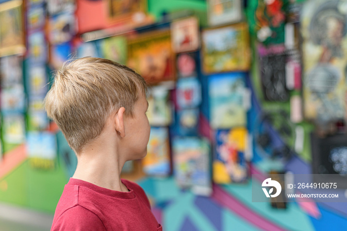 The boy looks at the paintings in the exhibition gallery.