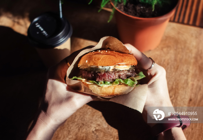 Burger in paper packaging, coffee and fries close-up. Food in a fast food restaurant. Macro photo of a burger with meat and vegetables, French fries and coffee. Fast food set