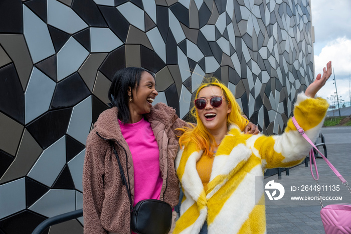 Stylish young friends laughing outdoors