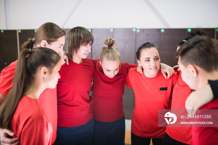 Large group of young sportswomen in red t-shirts standing in circle