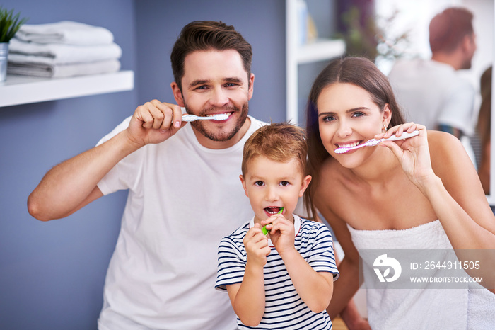 Portrait of happy family brushing teeth in the bathroom