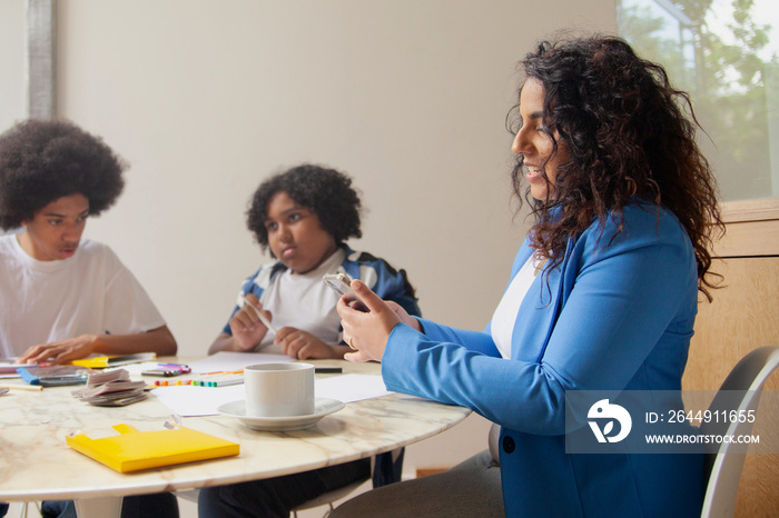 Mid-sized mother helping her children with homework and drinking coffee