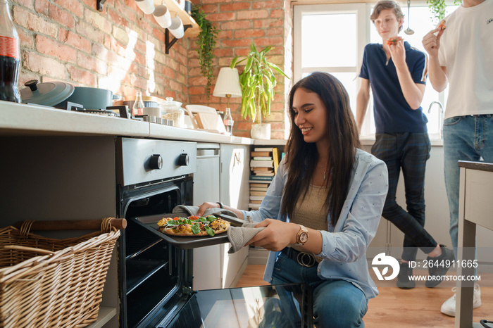 Shot of woman dressed in casual attire baking home made pizza for her friends.