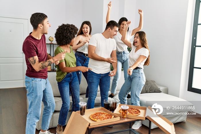 Group of young friends having party eating italian pizza and and dancing at home.