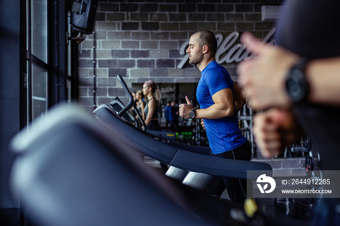 Young man in sportswear running on treadmill at gym.