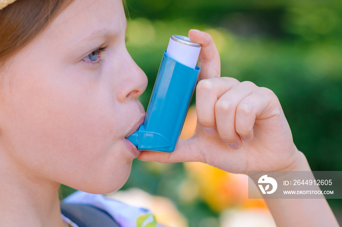 Girl having asthma using asthma inhaler for being healthy - shallow depth of field - focus on inhaler