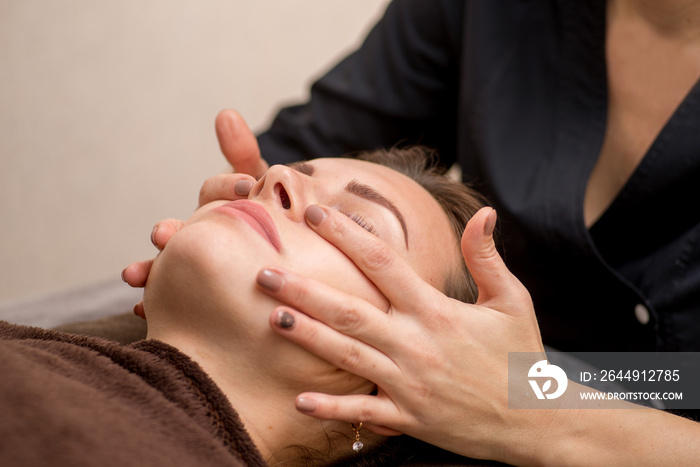 Facial massage in the spa. Beautician does facial massage. Body and face care