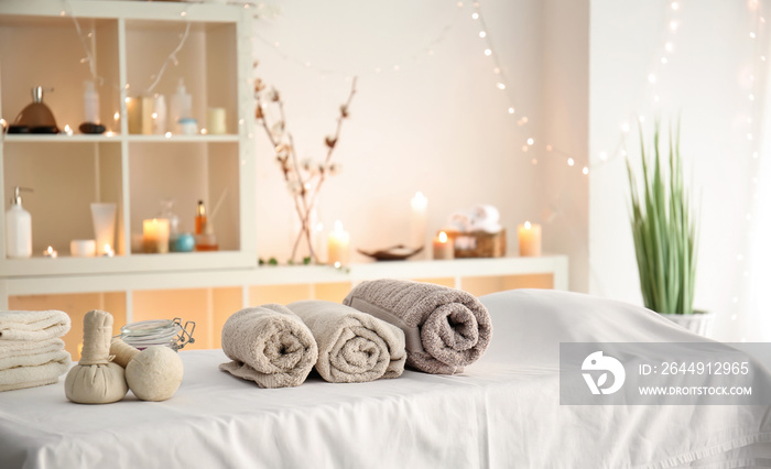 Soft towels with herbal bags on table in spa salon