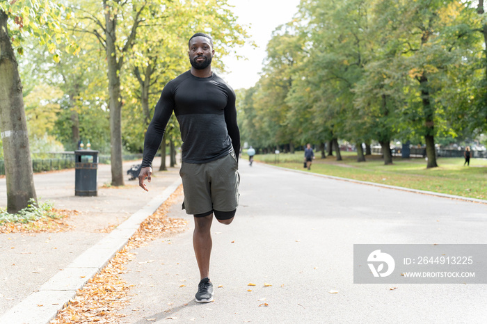 Portrait of athletic man stretching leg in park