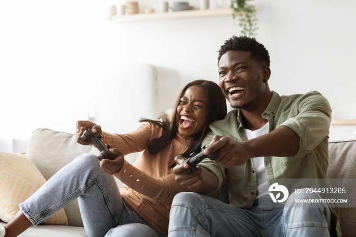 Happy black couple playing video games at home