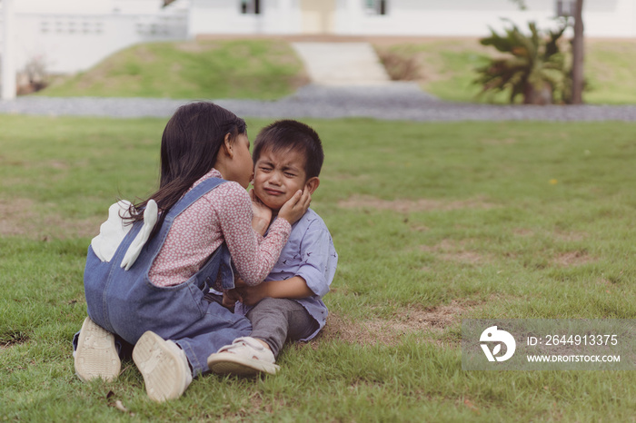 Asian sister is kissing and soothing crying little brother to make him feel better, concept of sibling kid, love, relation, friendship and growth of children in family life.