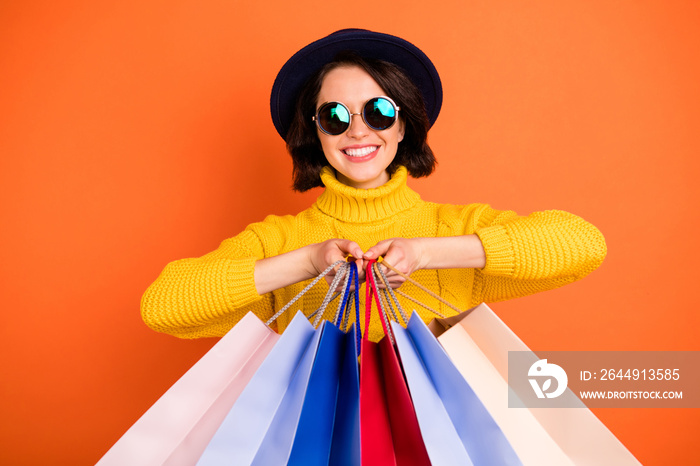 Photo of trendy charming excited nice good girlfriend wearing cap holding bags with something newly bought while isolated with orange background