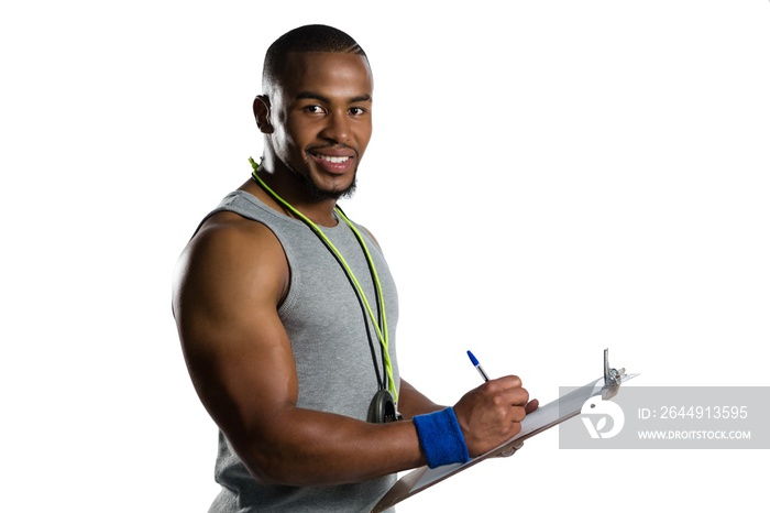 Portrait of smiling male rugby coach writing on clipboard