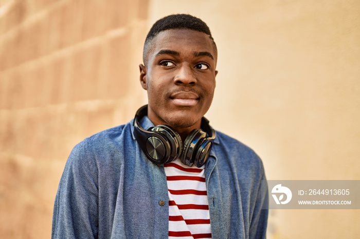 Young african american man with relaxed expression using headphones at the city.