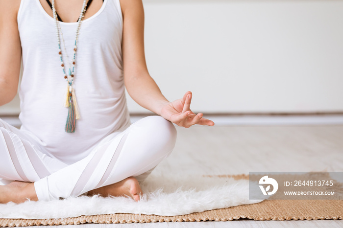 Healthy pregnancy lifestyle concept. Pregnant woman meditating in yoga lotus position, sitting on exercise mat with legs crossed and hands on knees in mudra.